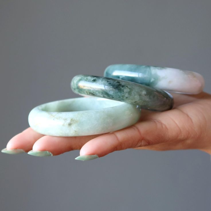 three bangle bracelets resting on a woman's hand