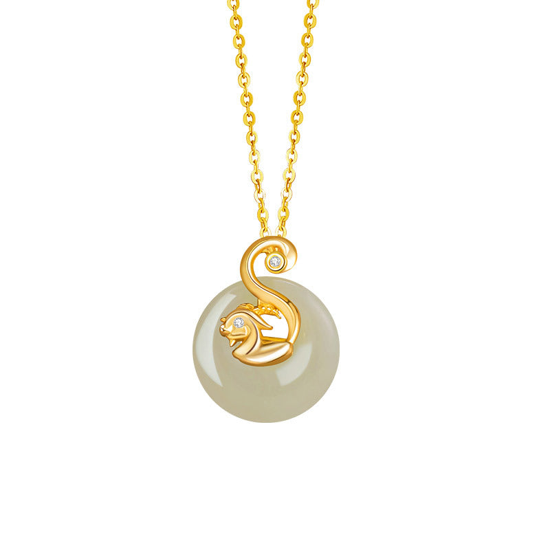 Close-up of a Birthright pendant necklace featuring a smooth, light-green Hetian jade disc adorned with a golden zodiac animal (likely a rabbit or cat) with diamond accents, suspended from a delicate gold chain.