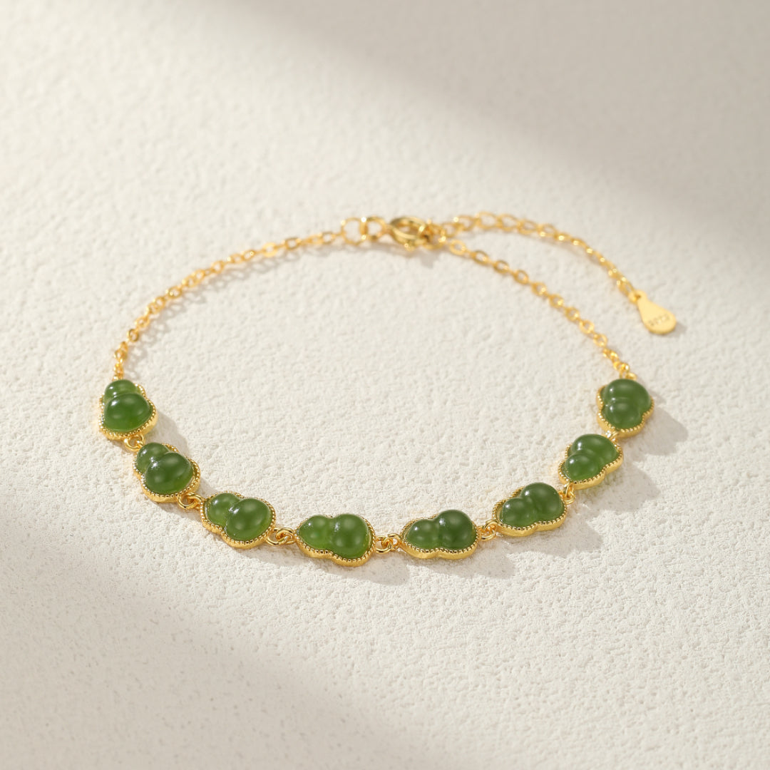 Gold plated silver bracelet with multiple small green jade gourd charms.