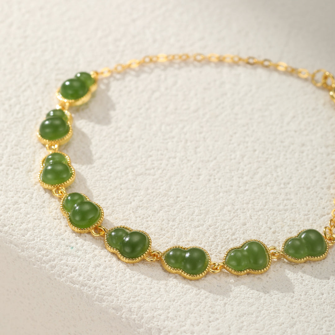 Gold chain bracelet featuring a row of carved green jade gourds, symbolizing good fortune.