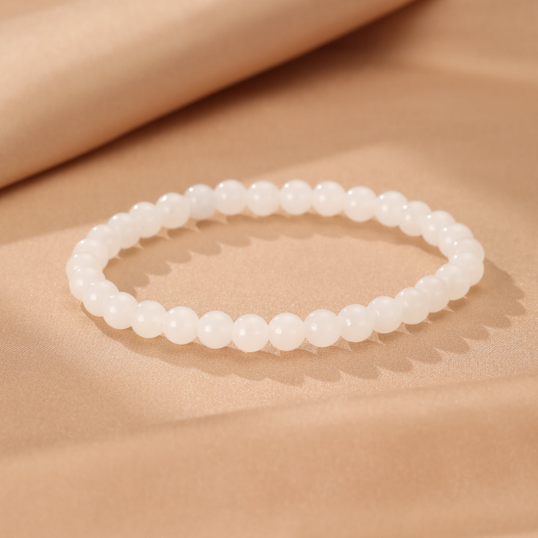 Full Measure bracelet made of smooth, white Hetian jade beads on a soft, neutral background.
