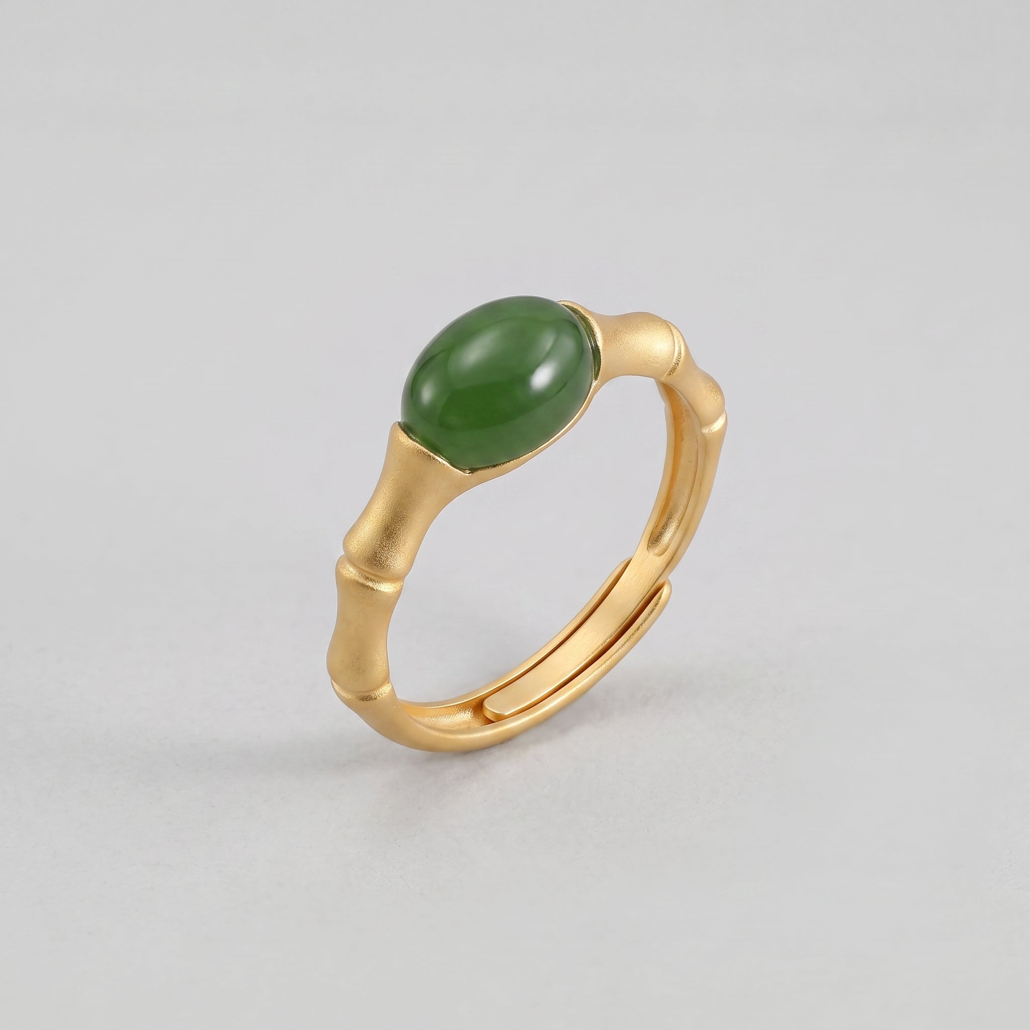 Gold bamboo-shaped ring with a smooth, oval green jade stone set in the center.