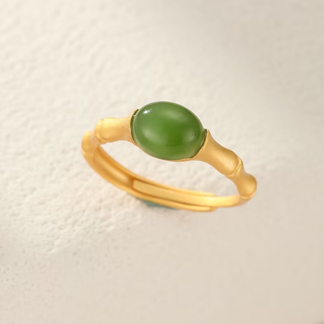 Gold-plated ring with a bamboo design holding a smooth, oval green jade stone.