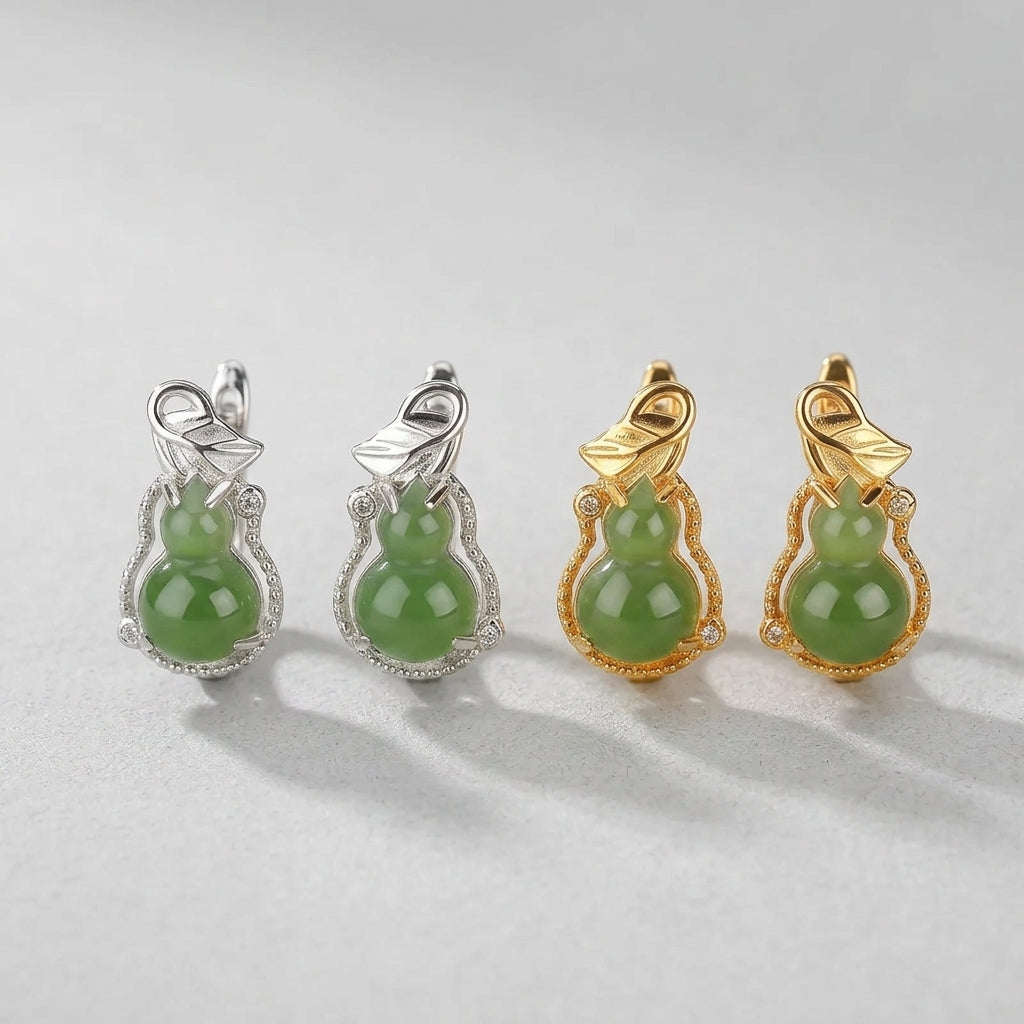 Close-up of two pairs of Harvest Green Jade Gourd Hoop Earrings, one pair in silver with clear stones and one pair in gold with clear stones, against a light gray background.
