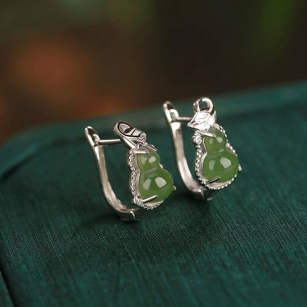 Harvest Green Jade Gourd Hoop Earrings feature polished green jade stones carved into gourd shapes, set in a silver-tone metal with intricate detailing.