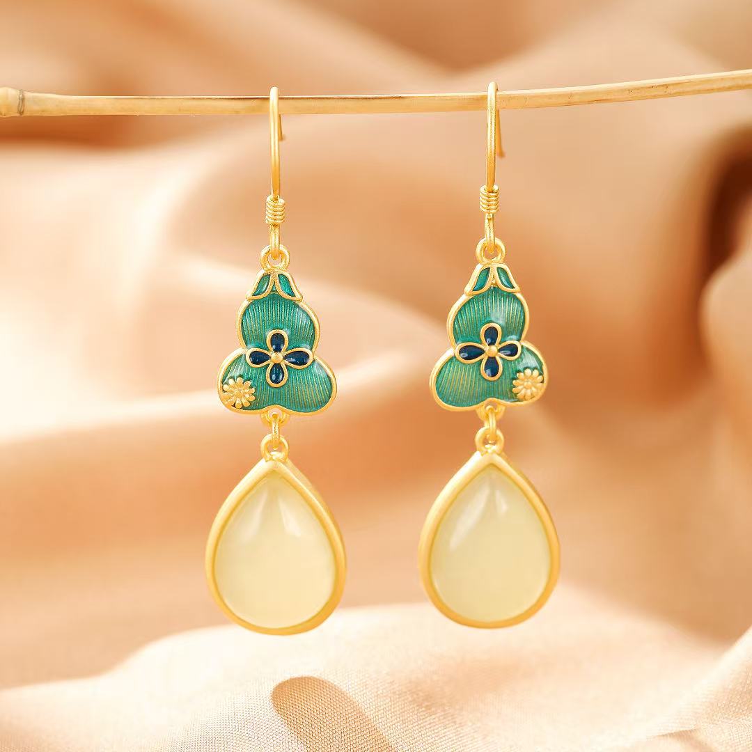 Gold plated silver earrings featuring teardrop-shaped jade pendants suspended from green enameled gourd charms adorned with blue flowers.