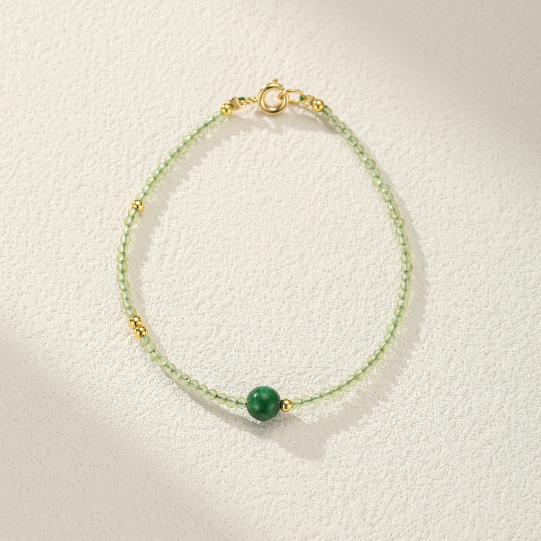 Delicate green jade beaded bracelet with gold accents and a central green jade bead.