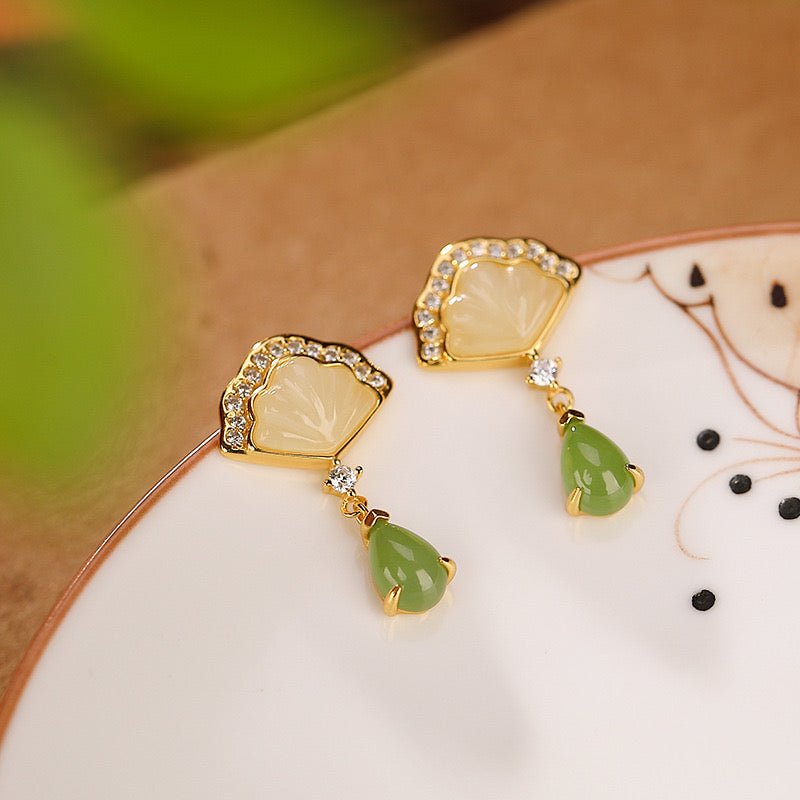 Slow Dance gold plated earrings featuring light green jade teardrop pendants and fan-shaped mother of pearl tops with cubic zirconia accents.