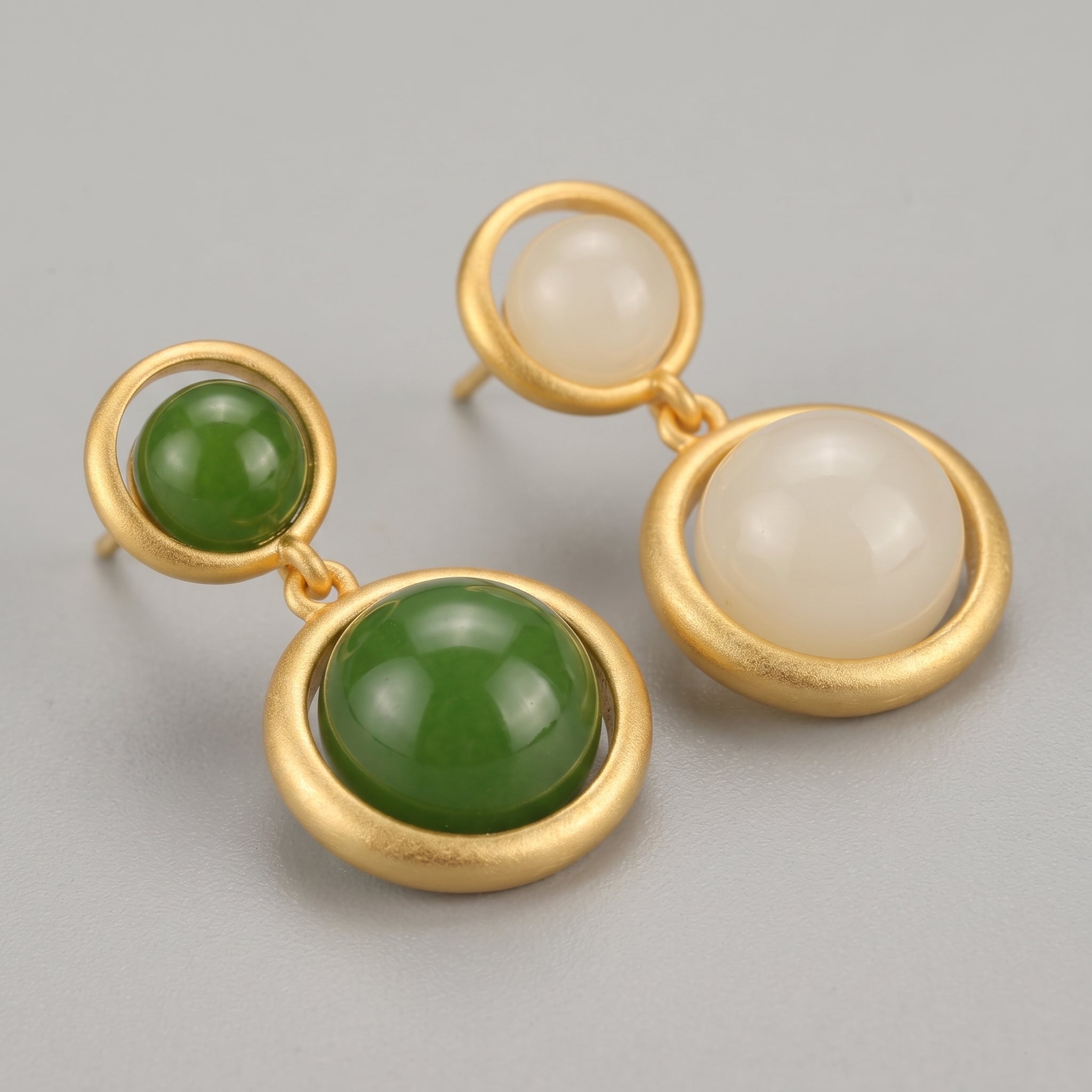 Solstice Hetian Jade Sun Drop Earrings featuring round green jade and white stone cabochons set in matte gold frames.