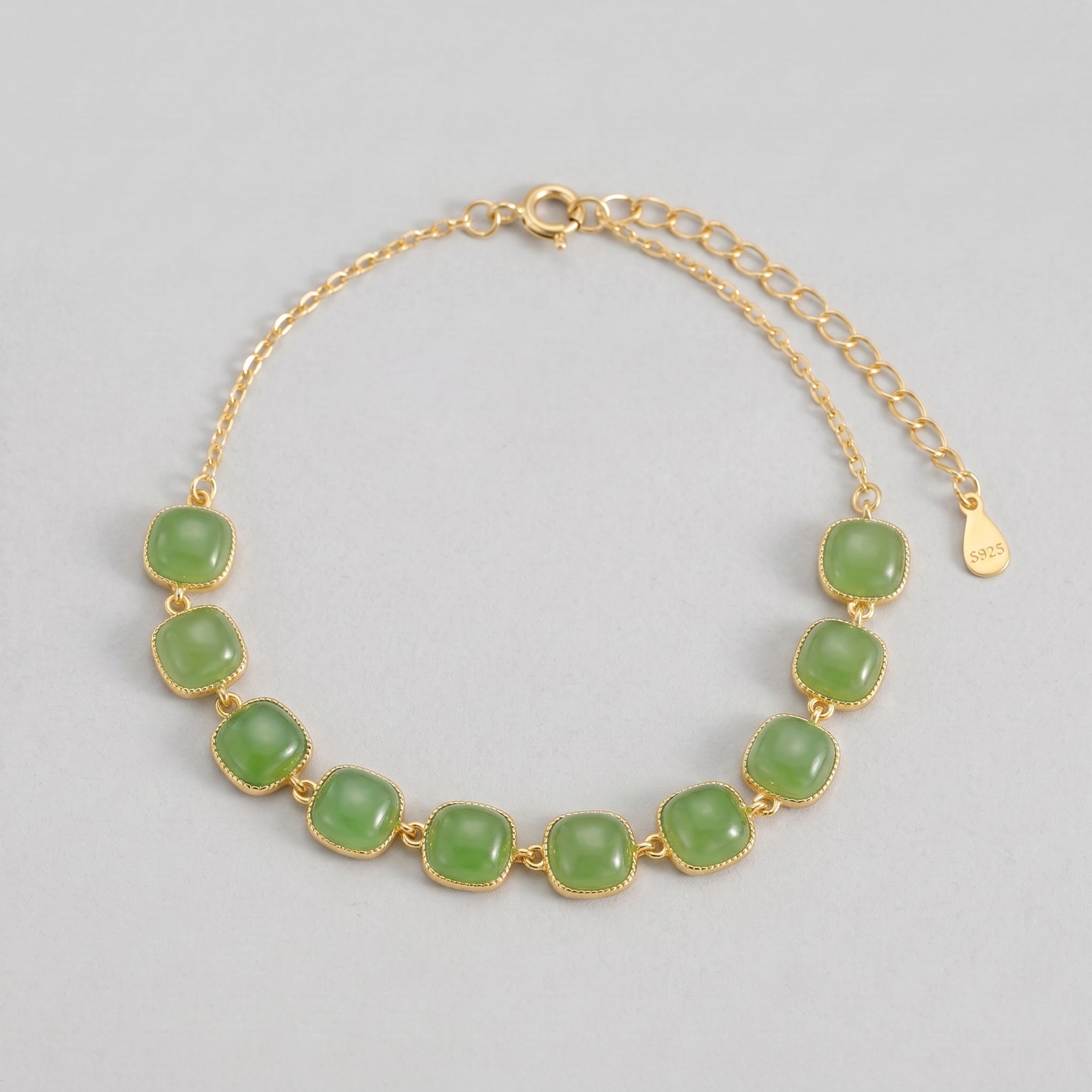 A delicate gold bracelet featuring a series of square-shaped green jade stones, set against a neutral gray background. The "Sunday Best" bracelet has a thin chain and an adjustable clasp with a "S925" stamp.