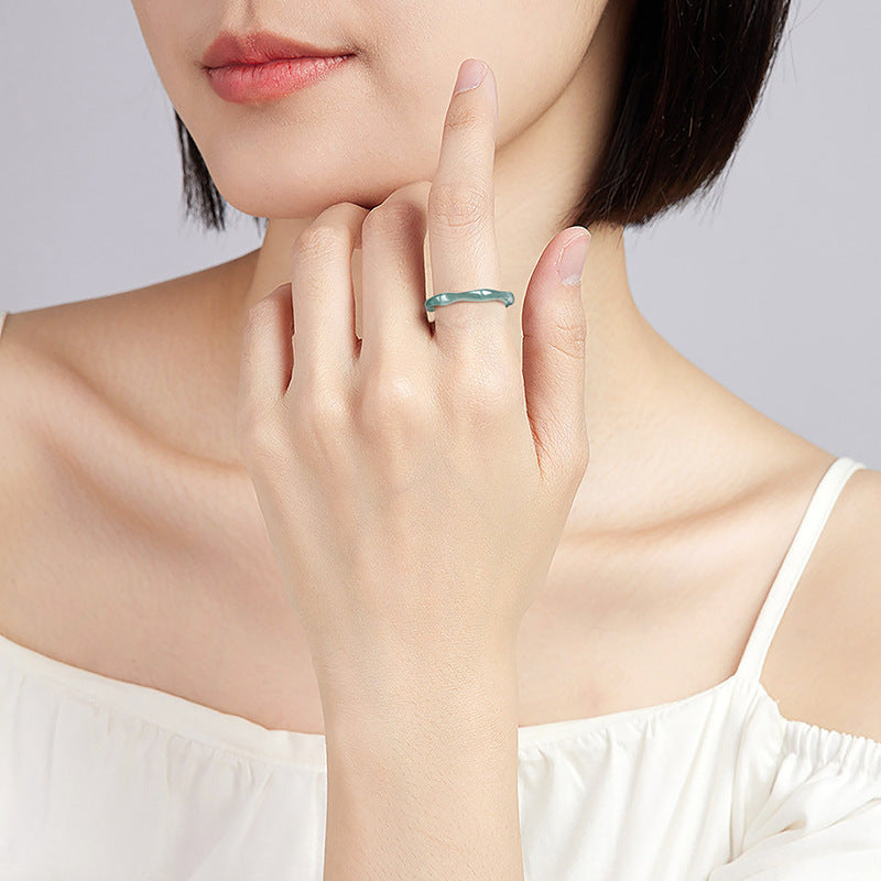 Close-up of a woman's hand wearing the After Rain Blue Jade Bamboo Ring on her index finger. The ring features a unique, wavy bamboo-like design and a translucent blue-green jade color.