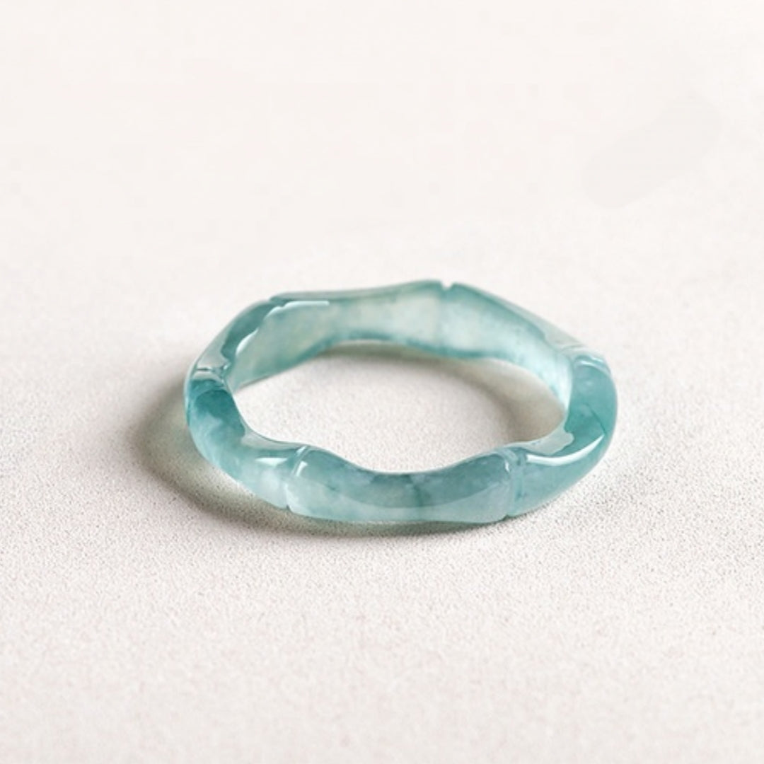 A translucent blue jade ring designed to mimic bamboo segments, showcased in a studio shot on a white surface.