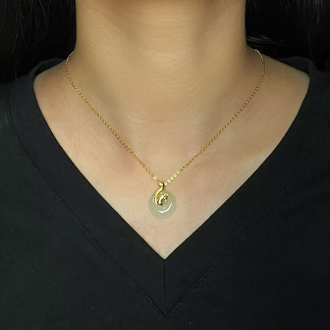 A woman wears a delicate gold chain necklace with a light green Hetian jade pendant featuring a golden zodiac animal charm.