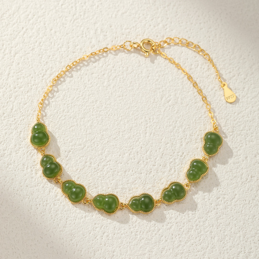 Gold chain bracelet featuring a series of small, carved green jade gourds set in gold-toned metal.