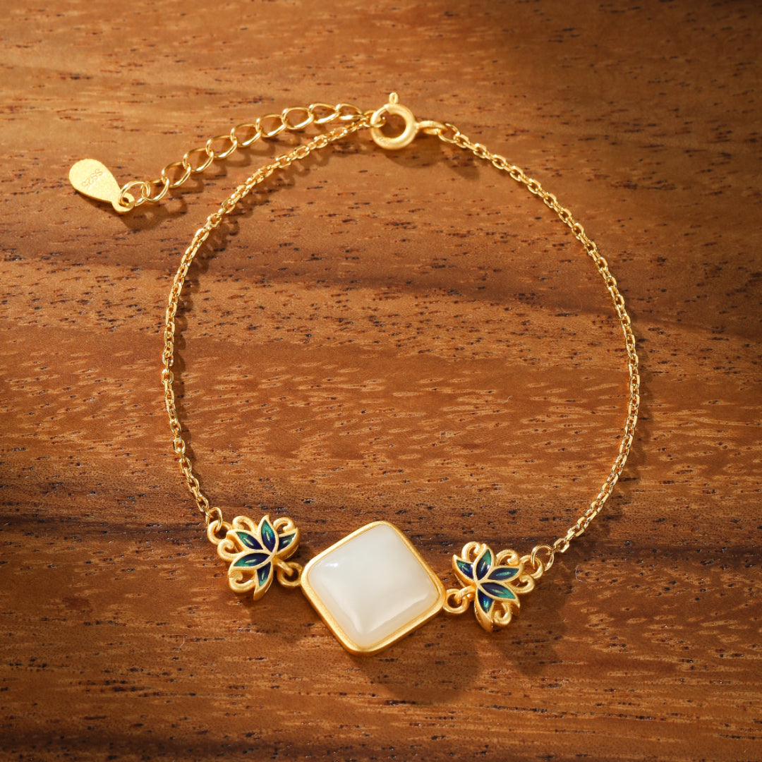 Gold plated silver bracelet featuring a square white Hetian jade gemstone set between two blue and green lotus flower charms on a delicate chain.