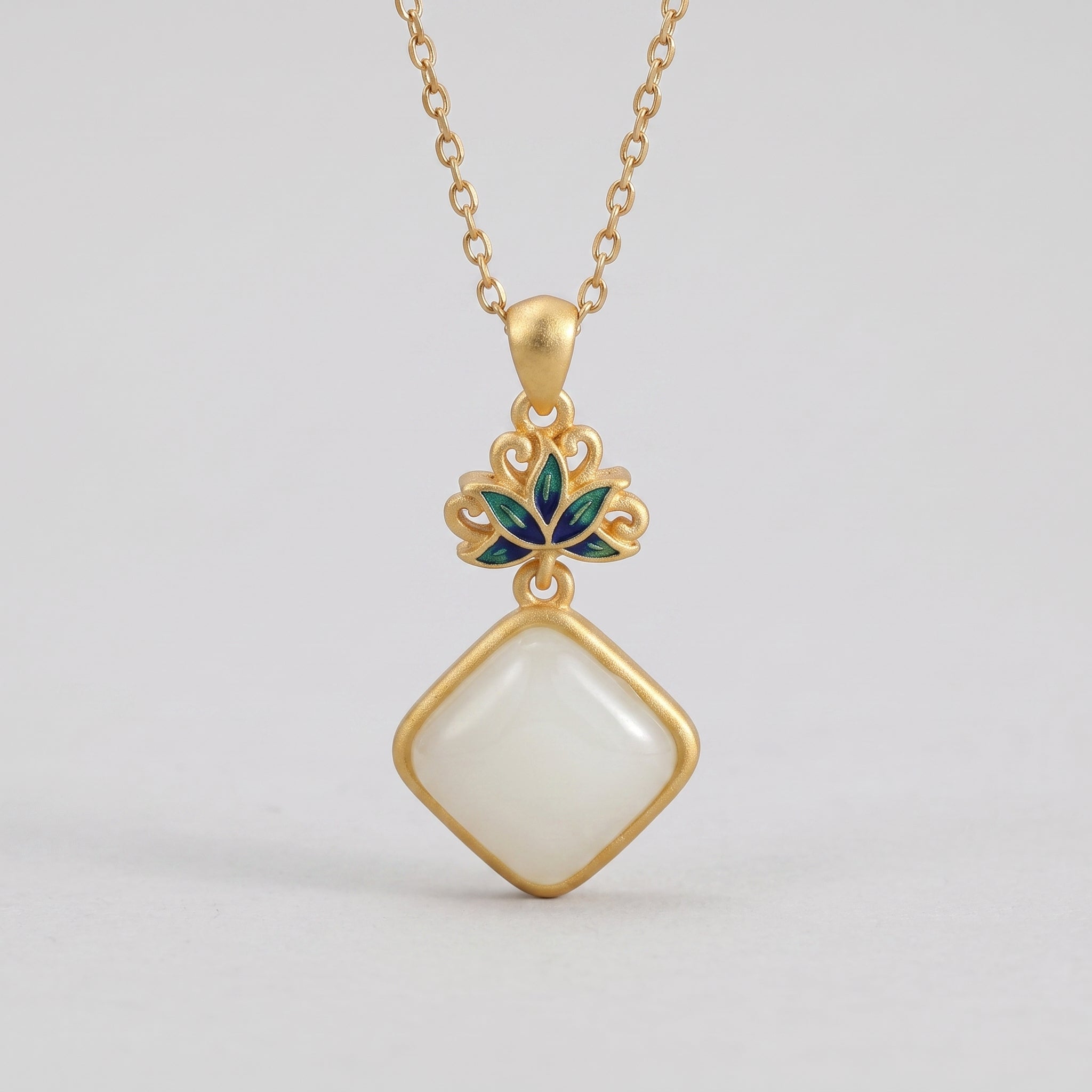 Gold necklace with a square white Hetian jade pendant, featuring a decorative lotus flower motif with green and blue enamel accents.