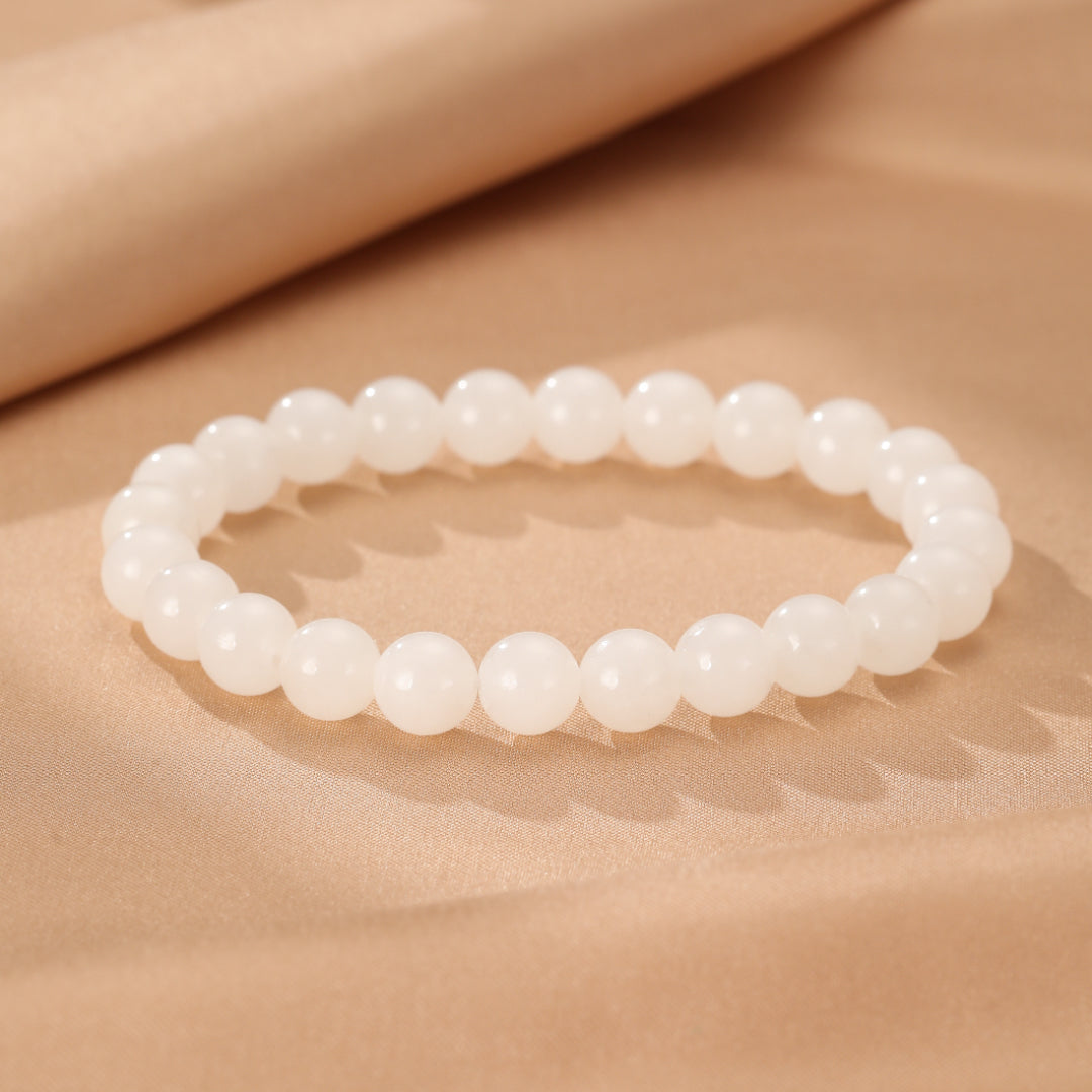 Full Measure Hetian Jade Beaded Bracelet with smooth white beads on a satin background