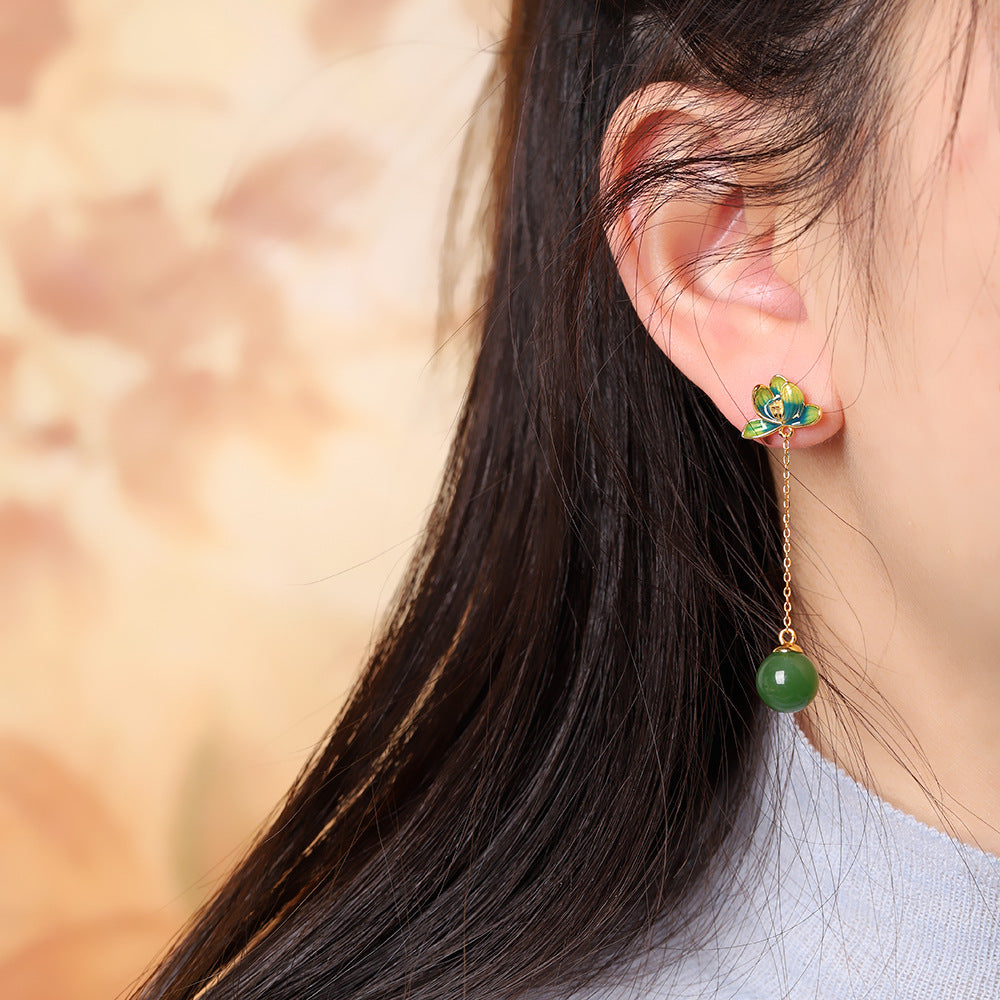 Close-up of a woman wearing Halcyon green jade lotus drop earrings, featuring a gold chain with a jade bead.