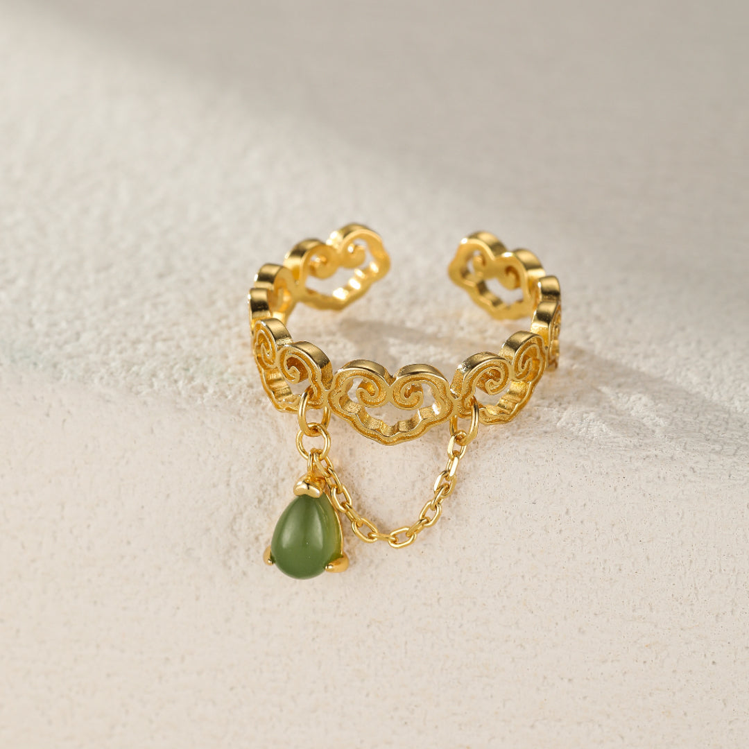 Gold-plated silver ring with a cloud design and a dangling teardrop-shaped green jade stone.