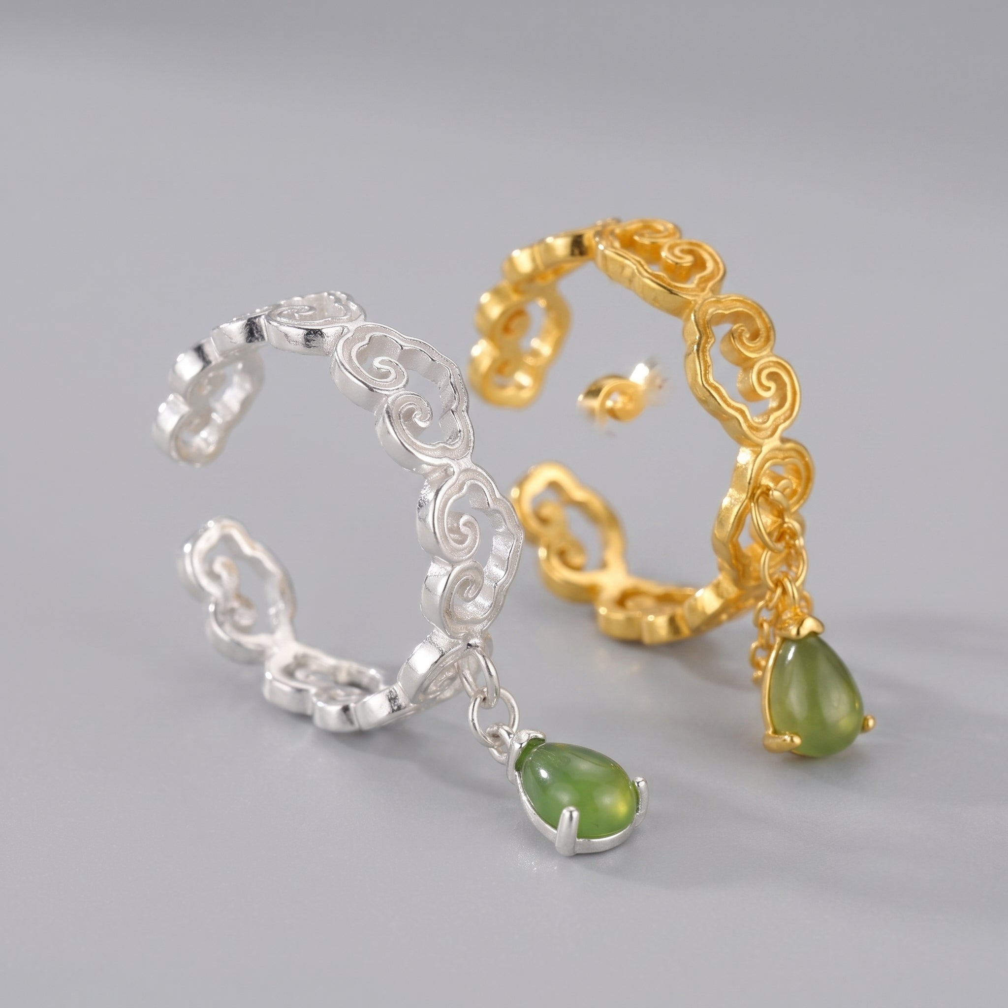 A gold and silver cloud-shaped adjustable ring with a dangling green teardrop-shaped gemstone charm.