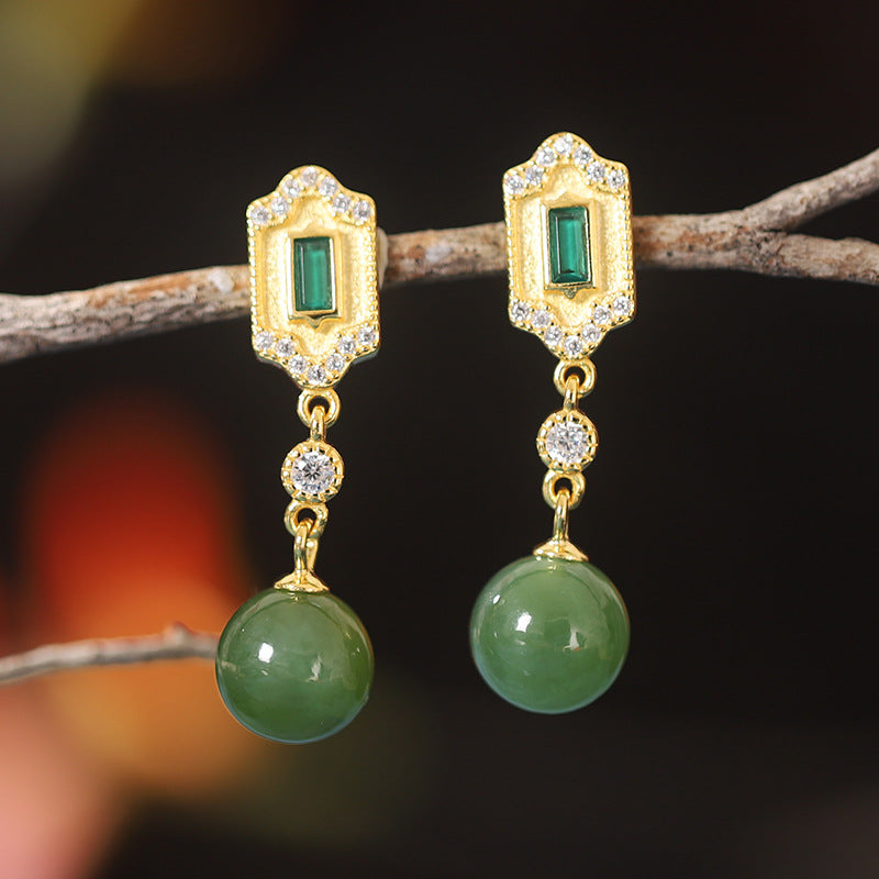 Kindred Green Jade and Emerald Drop Earrings featuring gold settings with inset green emeralds and dangling green jade beads.