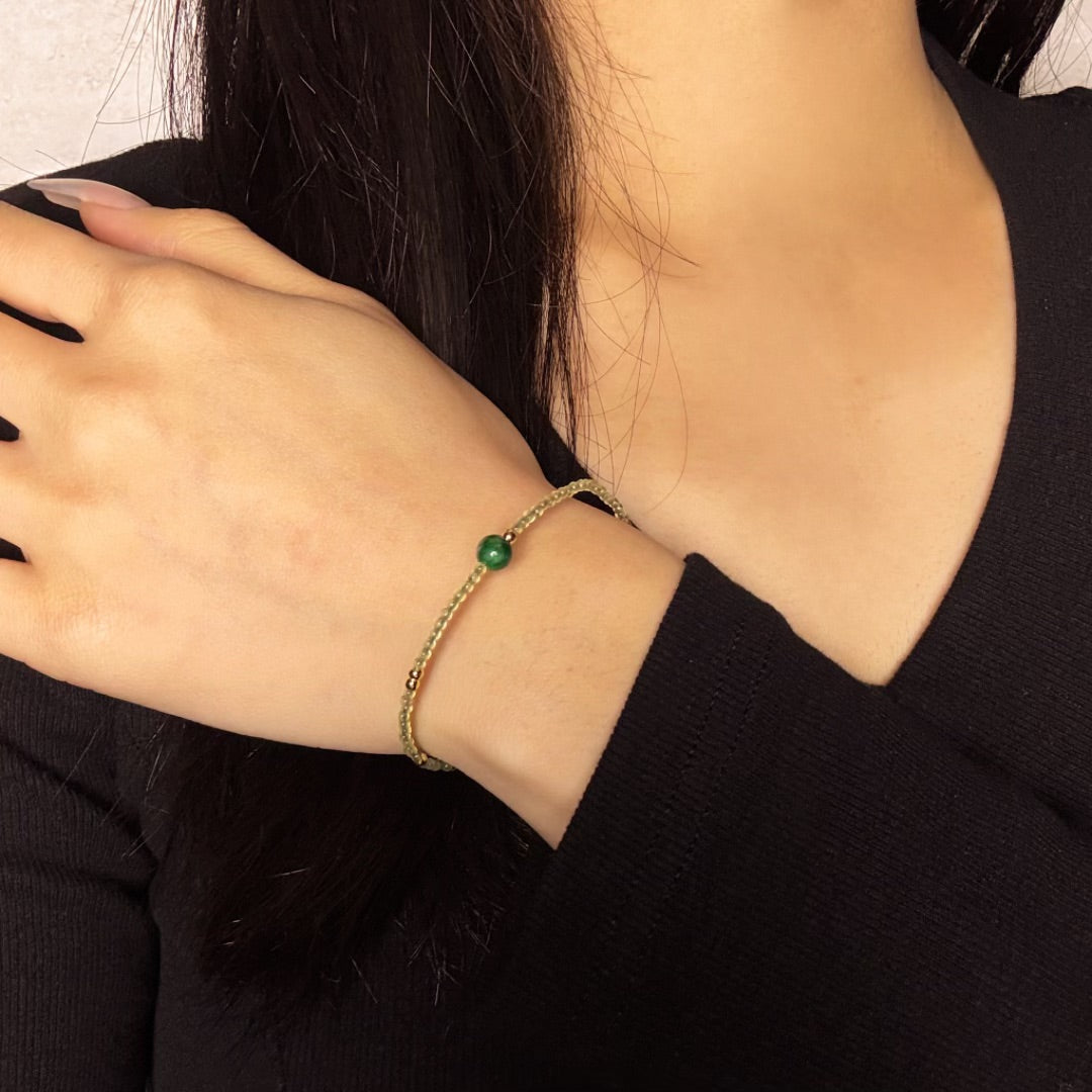 Close-up of a woman's wrist wearing the Meadow Green Jade Beaded Bracelet with a single green jade bead as a focal point.