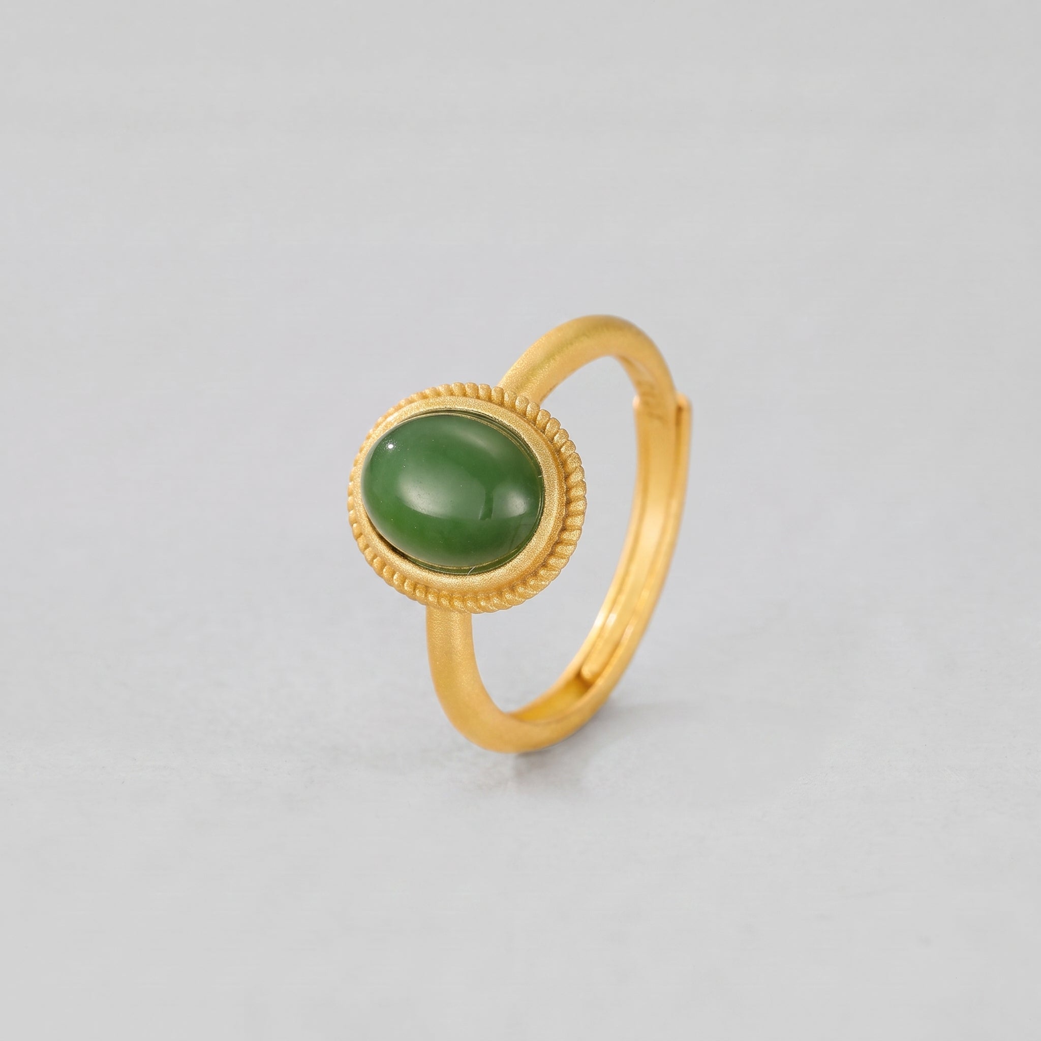 New Day ring featuring an oval, deep green jade cabochon set in a textured gold-tone band.