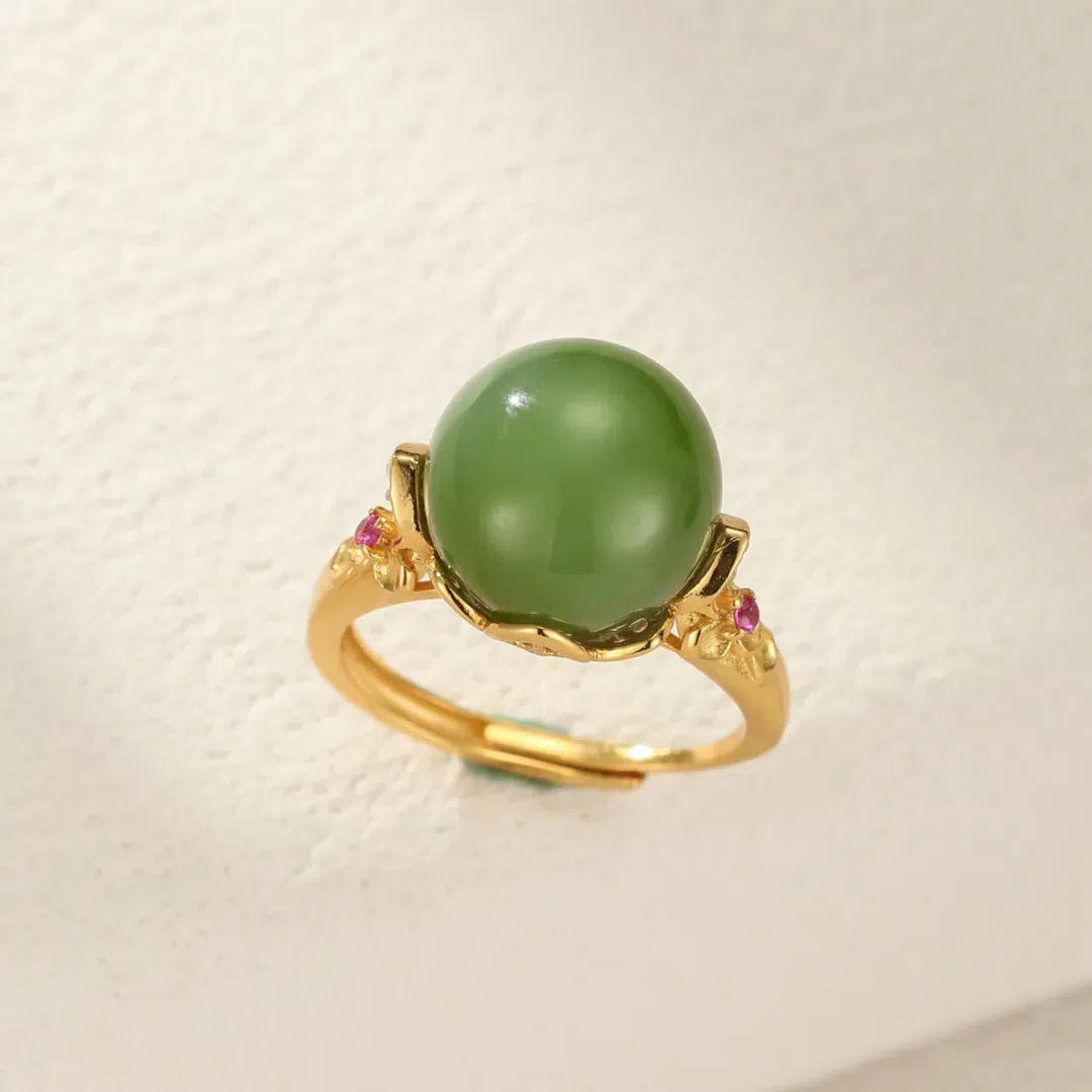 Sovereign ring with a large, smooth green jade solitaire stone, set in gold-plated silver with small pink accent stones on the band.
