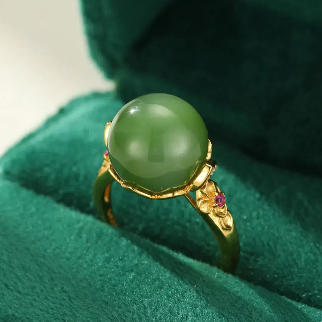 Close-up of a Sovereign green jade solitaire ring with gold-plated silver band, featuring delicate floral accents and small ruby details.