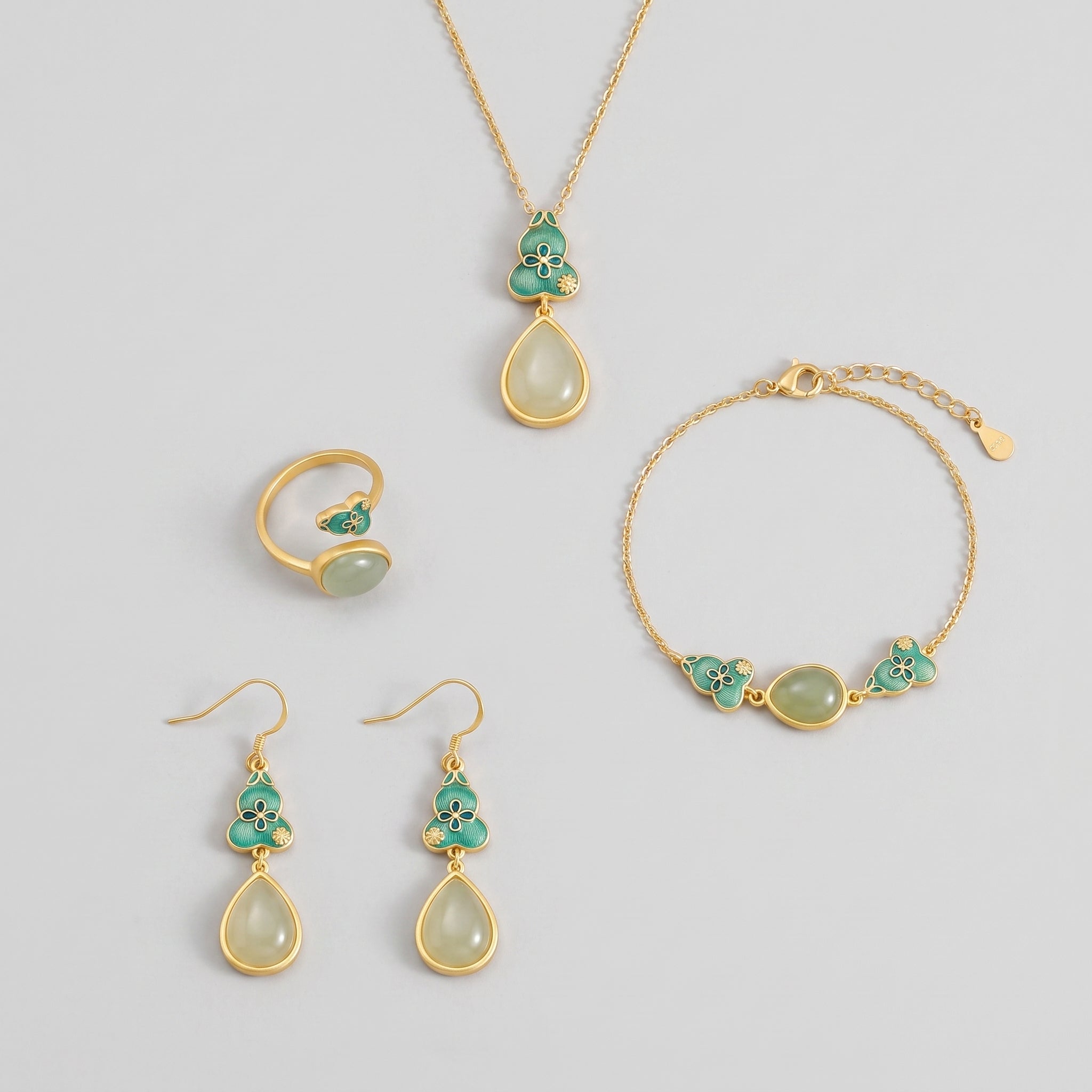 The "Twice Blessed" Hetian Jade Gourd Jewelry Set features a gold-plated necklace, bracelet, ring, and earrings, each adorned with a gourd-shaped pendant inlaid with pale jade and turquoise enamel.