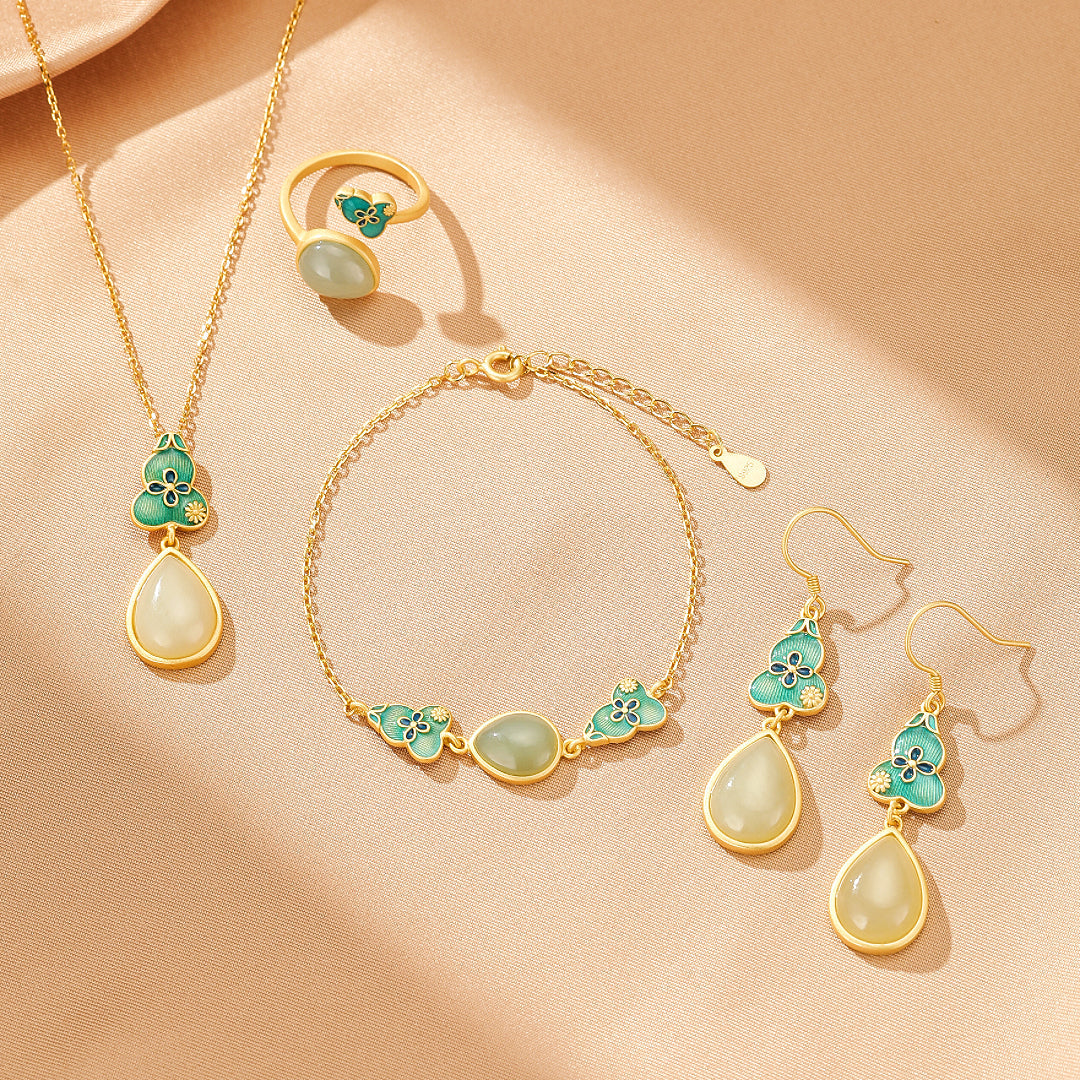 A delicate gold-plated silver jewelry set featuring Hetian jade. The set includes a pendant necklace with a teardrop jade charm, a matching ring, a bracelet with oval jade stones, and dangle earrings, all adorned with intricate teal enamel gourd and floral designs.